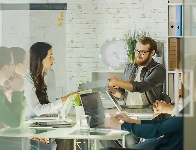 Équipe en réunion dans une salle de travail collaborative, illustrant une approche de co-construction pour la mise en place de solutions digitales éco-responsables.